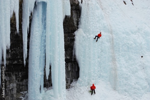 Two red clothed ice climbers on a frozen waterfall. 