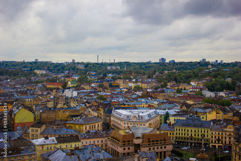 Lviv, old city view, with blue sky and fluffy clouds, summer. Aerial drone view of urban landscape, small buildings and trees. Background in the light fog or aerial perspective.