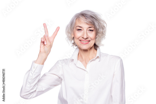 Close up portrait of senior grey-haired woman wearing elegant shirt standing over isolated white background smiling with happy face doing victory sign