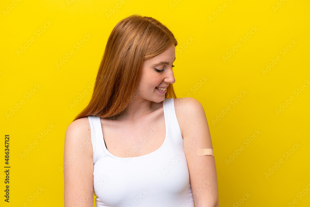 Young redhead woman wearing a band-aids isolated on yellow background with happy expression Young redhead woman wearing a band-aids isolated on yellow background with happy expression