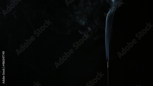 Flowing smoke from incense stick against black background	
 photo