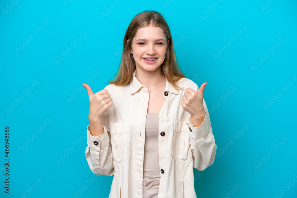Teenager Russian girl isolated on blue background with thumbs up gesture and smiling
