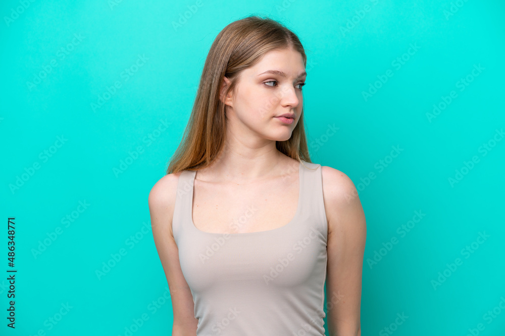 Teenager Russian girl isolated on blue background looking to the side