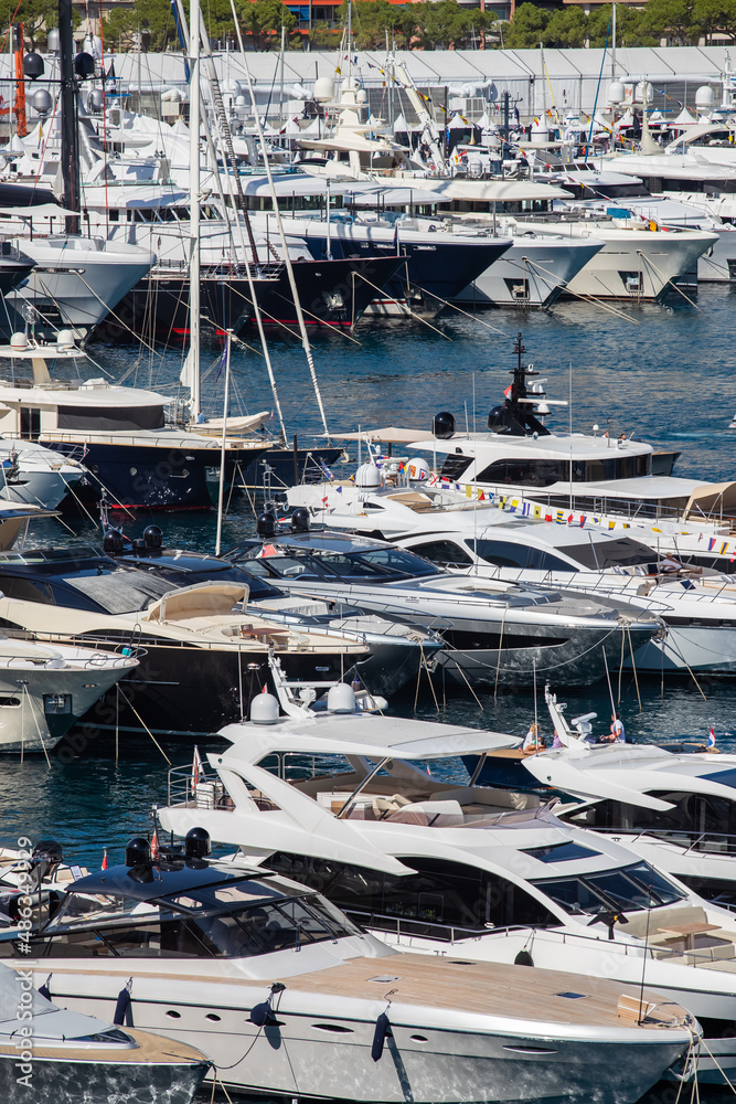 A lot of huge yachts are in port Hercule of Monaco at sunny day, Monte Carlo, many small boats are on background, interiors of motor boat, chilling zone of megayachts, sun reflections on glossy boards