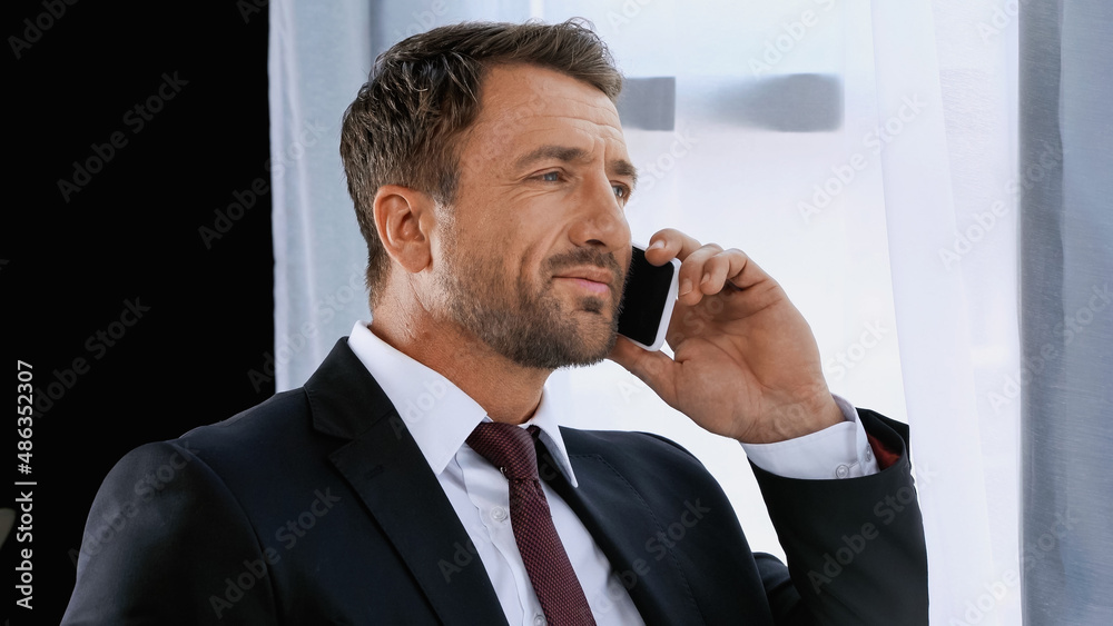 businessman in suit smiling while talking on mobile phone in office businessman in suit smiling while talking on mobile phone in office
