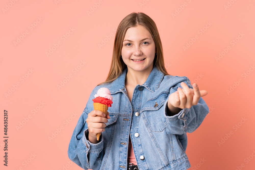 Teenager Ukrainian girl with a cornet ice cream isolated on pink background inviting to come with hand. Happy that you came Teenager Ukrainian girl with a cornet ice cream isolated on pink background inviting to come with hand. Happy that you came
