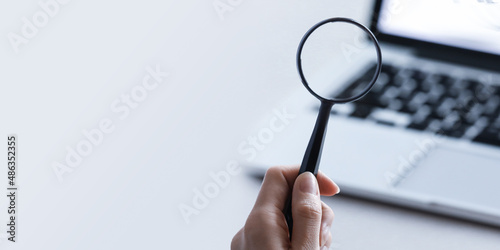 Magnifying glass put on close up of Laptop computer. Internet search concept. Wide banner or panorama. 