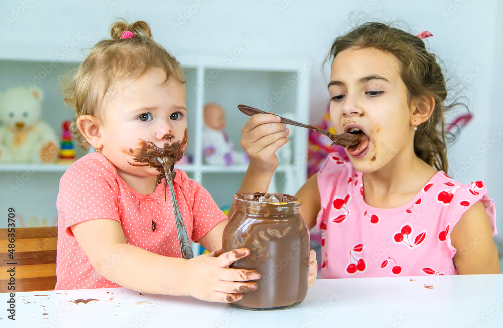Children eat chocolate sweets a lot. Selective focus. Children eat chocolate sweets a lot. Selective focus.