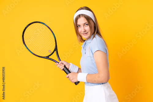 Teenager Ukrainian girl tennis player isolated on yellow background playing tennis © luismolinero