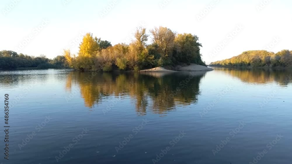 the river and the opposite bank with a forest in bright autumn foliage under a blue sky. water flowing calmly on a quiet windless day the river and the opposite bank with a forest in bright autumn foliage under a blue sky. water flowing calmly on a quiet windless day