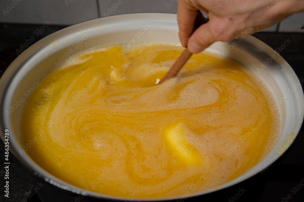 Cooking of yellow and green marijuana butter in hot water in kitchen Cooking of yellow and green marijuana butter in hot water in kitchen