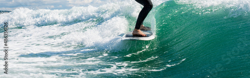 Wakeboarding. Close up of woman in wetsuit learning to wakesurfing behind wakeboard boat. Female surfing motorboat waves on river. Banner image with copy space