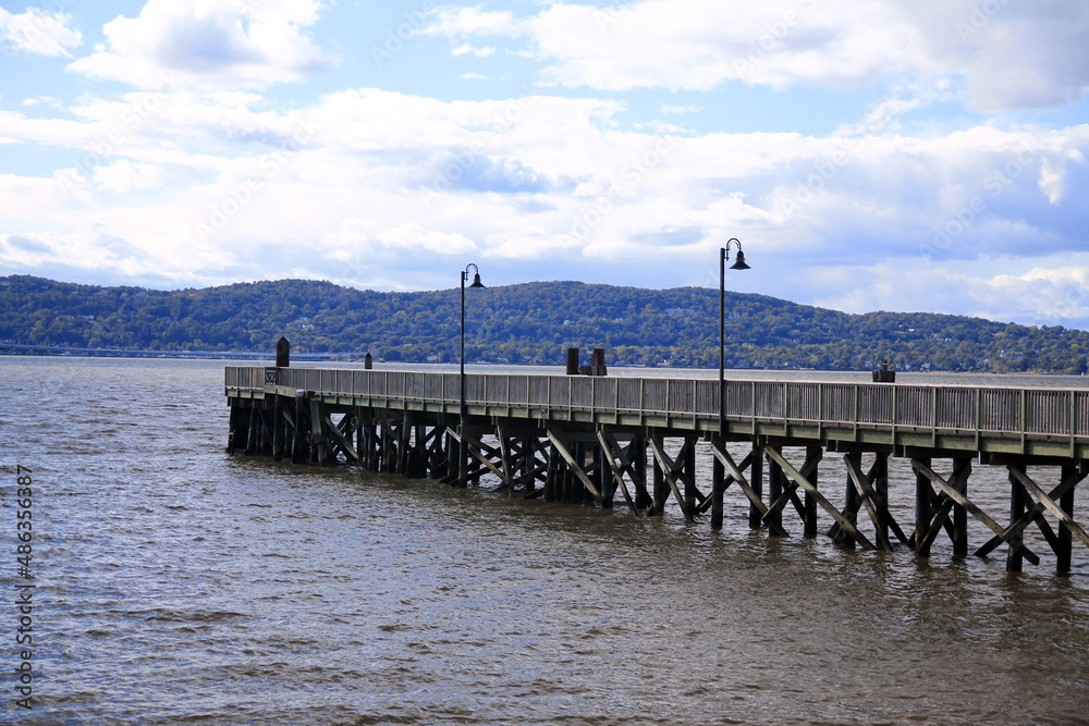 The wooden pier with the black lamps on the brown river The wooden pier with the black lamps on the brown river