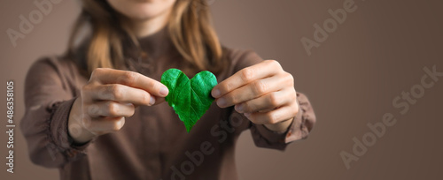 Woman on redshirt hands holding heart-shaped leaves CSR ,ESG, Eco green sustainable living, environmental, social and corporate governance. Environmental and Ecology Care Concept. 