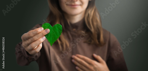 Woman on redshirt hands holding heart-shaped leaves CSR , ESG, Eco green sustainable living, environmental, social and corporate governance. Environmental and Ecology Care Concept.