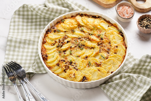 Schilderij op canvas Slices potato casserole with red onions, fresh thyme and rosemary on green check