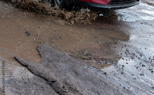 Splash of water of muddy puddle out of car front wheels on broken road © Irik