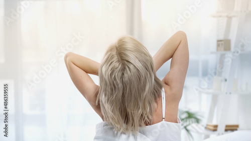 back view of young woman stretching in bedroom
