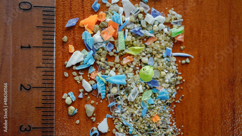 Macro shot of authentic non-recyclable microplastics particles with a ruler from the sand on the beach. Selective focus with shallow depth of field.