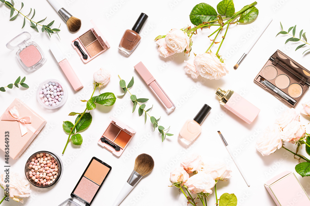 Bright spring composition with assortment of decorative cosmetic products on white background with aromatic roses and eucalyptus leaves top view. Spring cosmetic sale and promo banner.