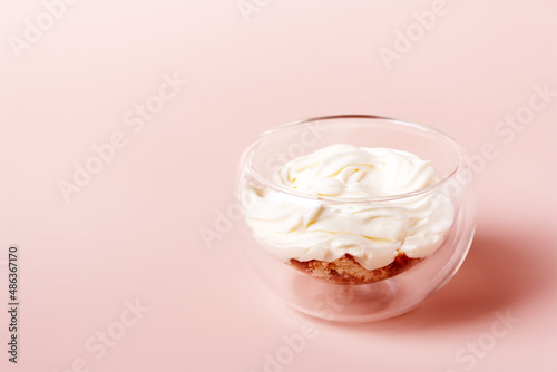 one serving of tiramisu in a glass cup on a beige background with copy space