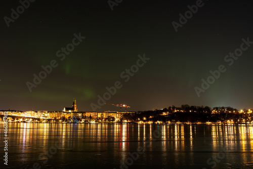 Northern lights, or Aurora Borealis, over Stockholm city skyline on a cold winter night with frozen water. Night view of Södermalm in Stockholm, Sweden. Photo taken February 10, 2022.