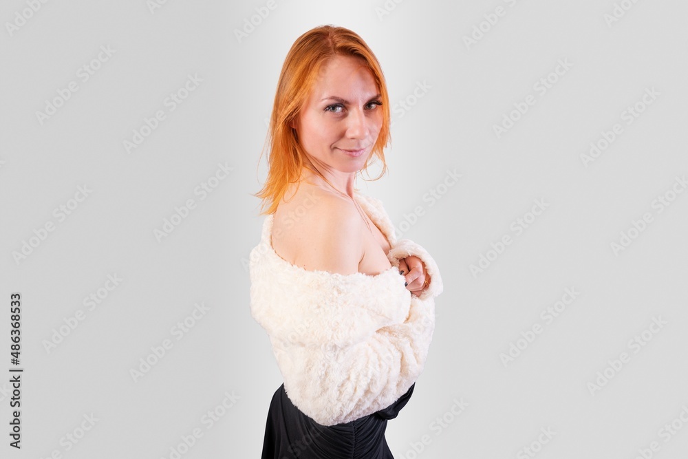 Sexy girl in a white fur cape on bare shoulders, on a gray background Sexy girl in a white fur cape on bare shoulders, on a gray background