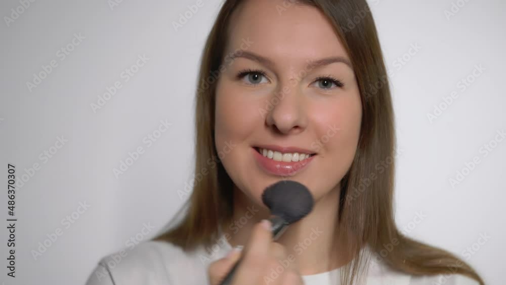 Young beautiful woman doing makeup. The girl applies powder with make up brush. Young beautiful woman doing makeup. The girl applies powder with make up brush.
