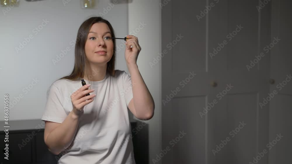 Young beautiful woman doing makeup. The girl applies mascara with make up brush. Young beautiful woman doing makeup. The girl applies mascara with make up brush.