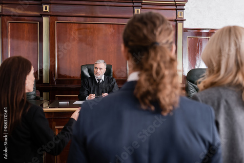 prosecutor talking to senior judge near accused man and advocate in court photo