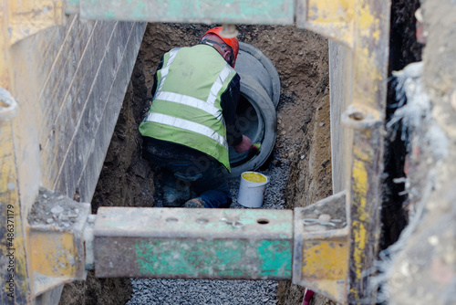 Bild auf Leinwand Deep drainage works and groundworker installing concrete pipe protected by trenc