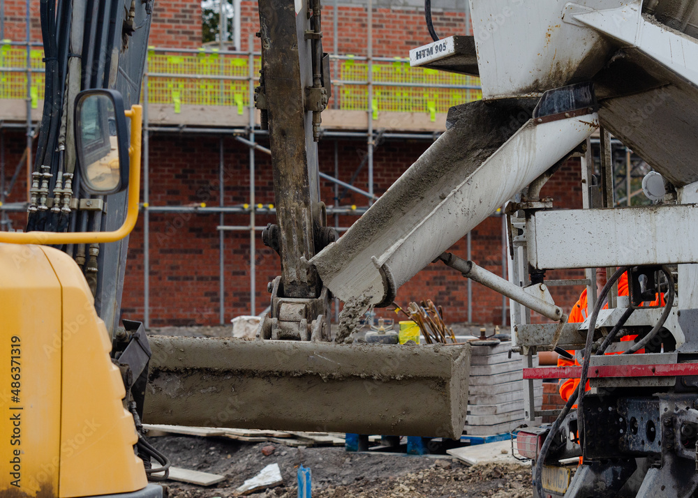 Fototapeta premium Exavator bucket filled with wet concrete to bring it to plce of concrete works on building site