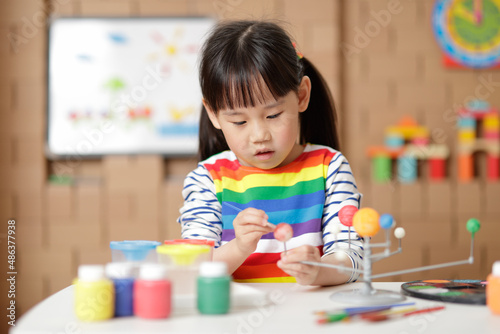 young girl painting swivelling solar system toy at home