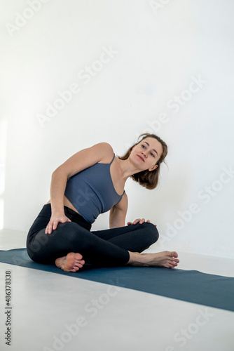Beautiful young woman working out in gym, doing forward bend yoga exercise on blue mat, close-up.