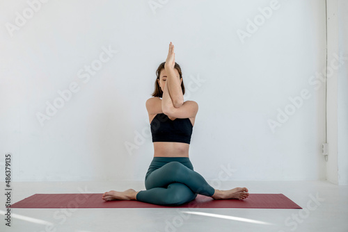 Millennial girl in a calm color of bodily loose clothes meditates in the lotus position.