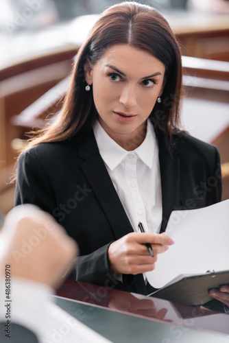 Obraz na plátně brunette prosecutor looking at blurred judge while holding lawsuit in court