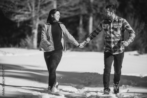 Couple running and holding hands in the winter snowy forest. Selective focus photo