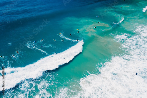 Surfers on surfboard and waves in blue ocean. Aerial view