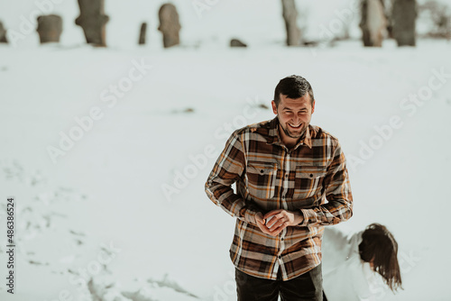 Snowball fight. Winter couple having fun playig in snow outdoors. Young joyful happy lovers. Selective focus.