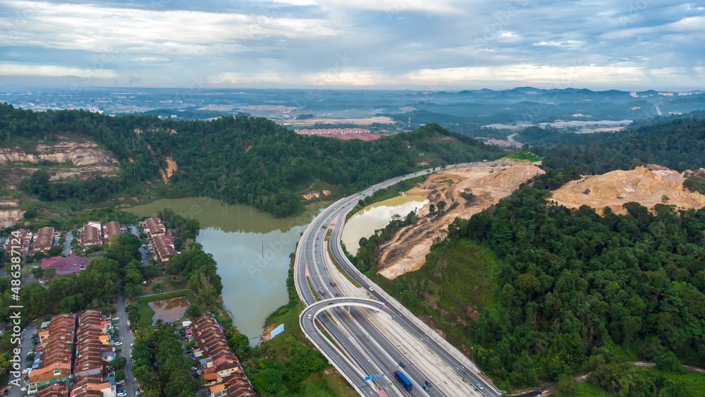 Fototapeta premium Aerial view of residential area with green asphalt road and residential houses directly above viewpoint. View of suburbs and city district. Real estate and housing market concept.