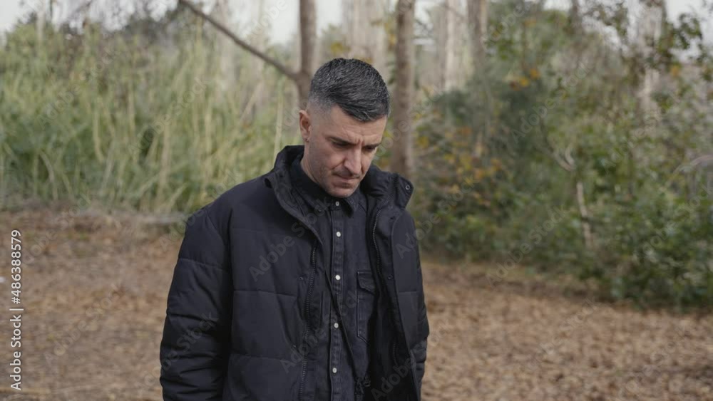 A man hangs his head, contemplating life as he walks alone through a secluded nature trail in slow motion. A man hangs his head, contemplating life as he walks alone through a secluded nature trail in slow motion.
