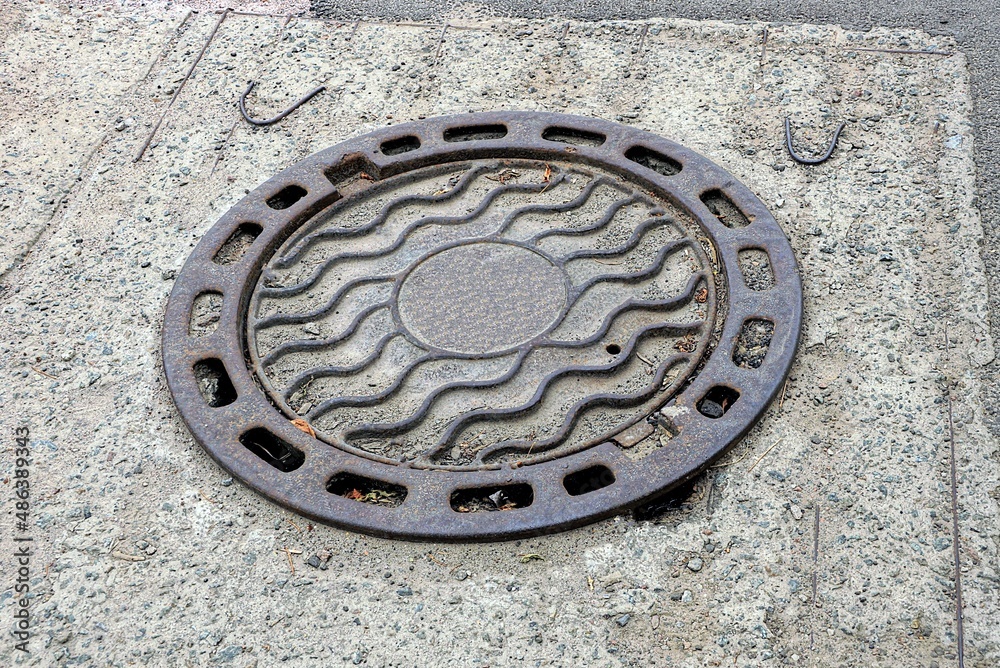 one brown closed iron manhole laying on the road in concrete one brown closed iron manhole laying on the road in concrete