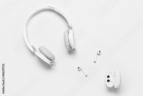 Modern headphones and earphones on white background