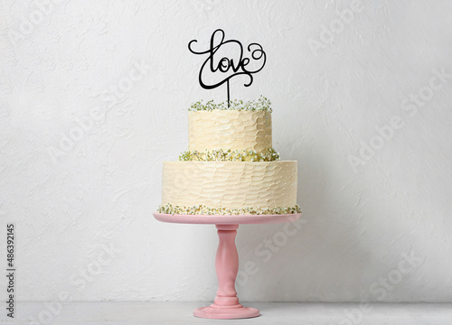 Dessert stand with beautiful wedding cake and topper with word LOVE on table