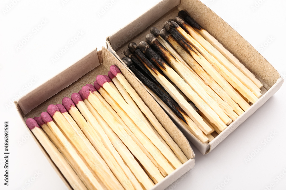 Matchboxes with whole and burnt matches on white background, closeup. Emotional burnout concept