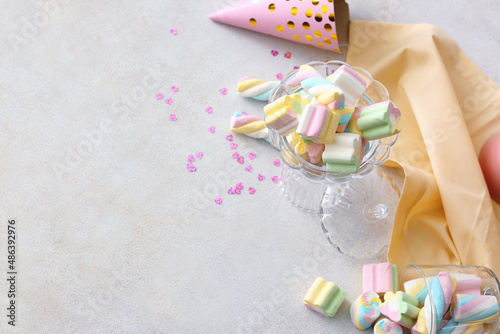 Composition with tasty marshmallows  party hat and confetti on light background