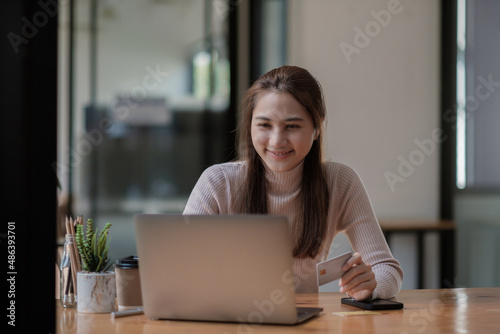 Portrait smiling asian woman resting and shopping online at home, Happy woman using laptop and credit card for online shopping. Online payment concept.