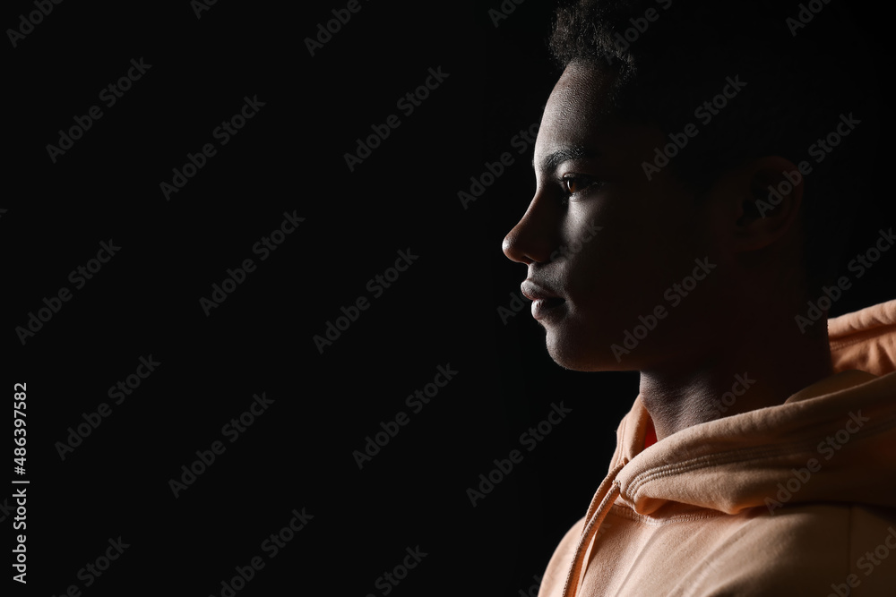 Silhouette of African-American teenage boy in hoodie on black background