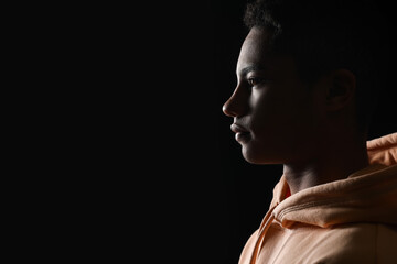 Silhouette of African-American teenage boy in hoodie on black background