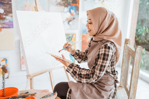 muslim asian female artist painting on canvas